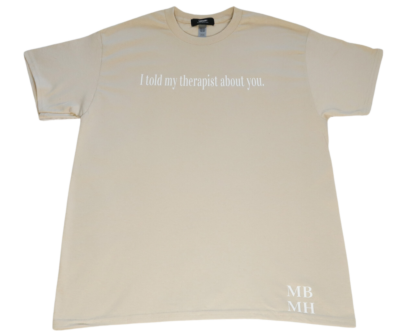 Short sleeve sand colored t-shirt with white vinyl lettering with phrase “I told my therapist about you.”